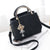 Stylish black shoulder bag with gold handle and decorative charm, perfect for women's fashion and daily use.