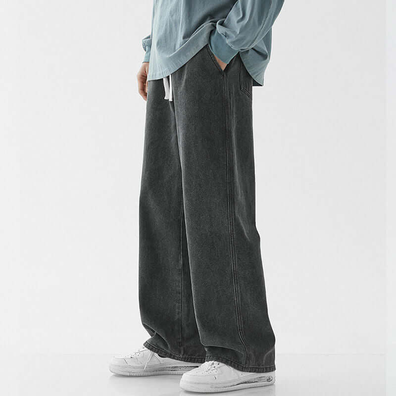 Men's casual loose straight jeans in dark gray, styled with a blue top and white sneakers.